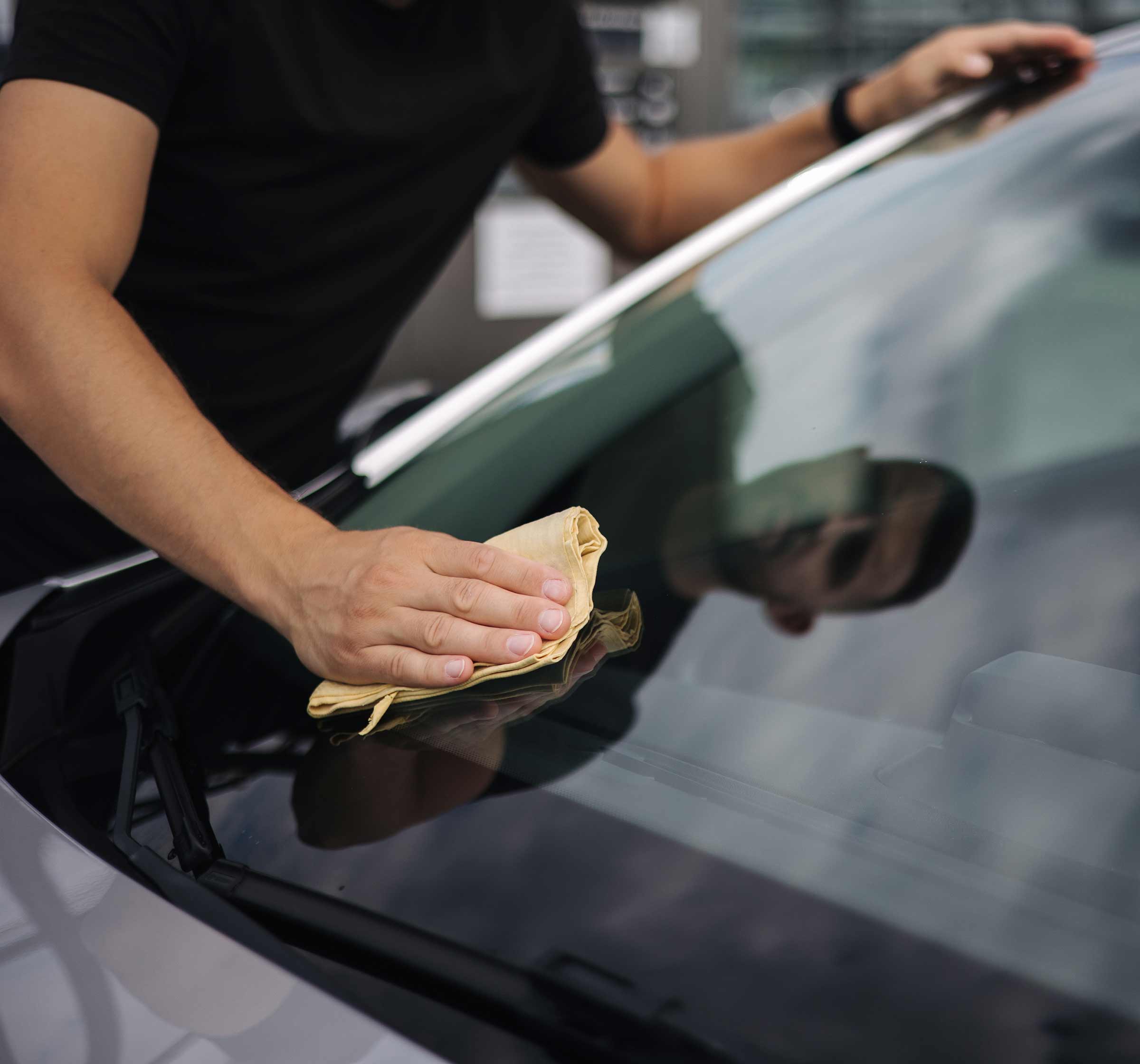 auto glass technician cleaning windshield